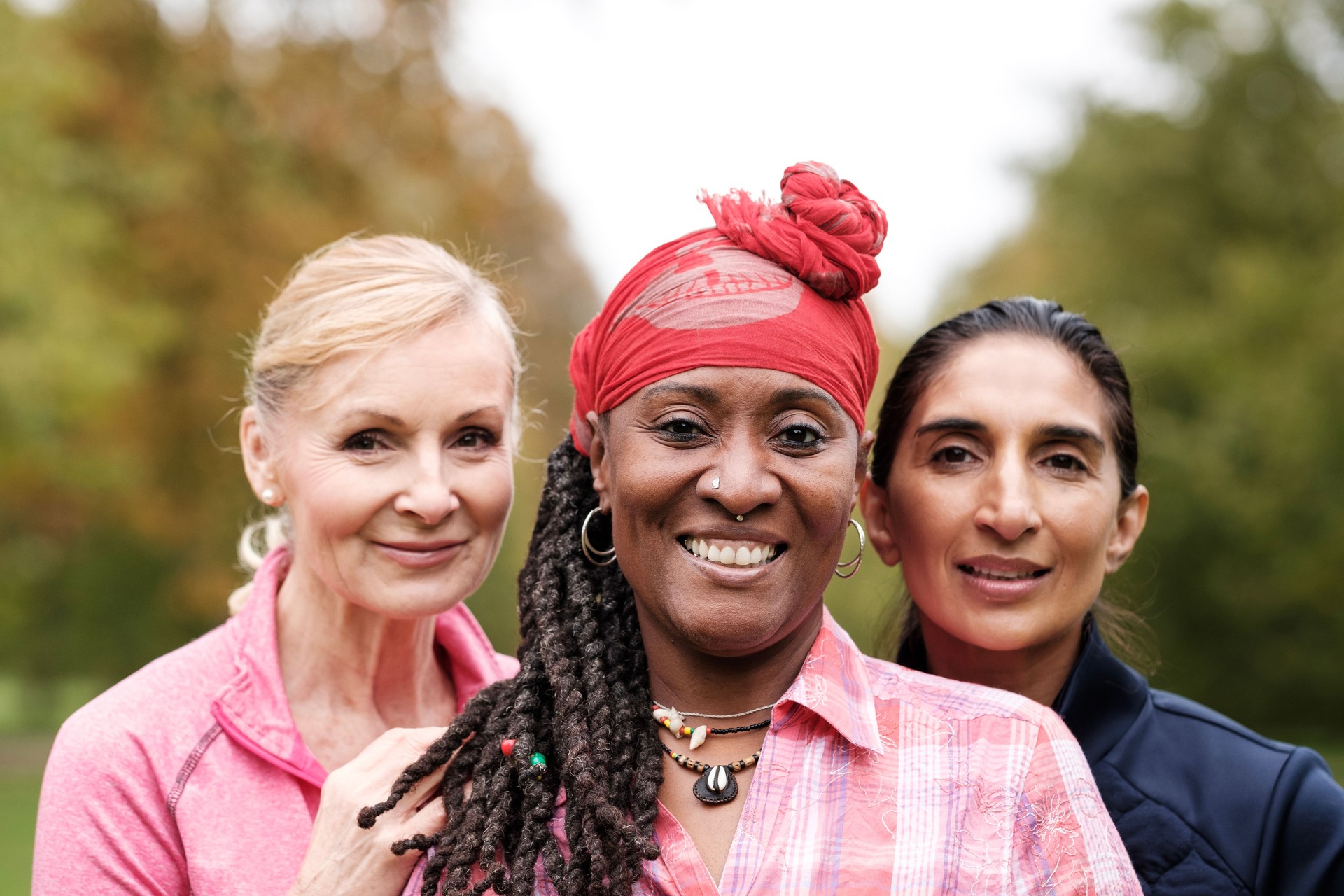 Three happy senior friends women are looking at camera outdoors.